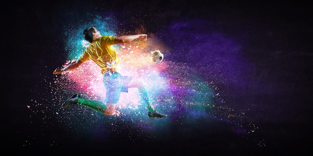 Boy playing soccer hitting the ball on colourful background. Mixed media