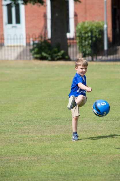 Photo boy playing soccer at park
