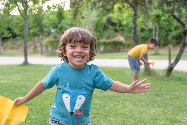 Photo boy playing toss paper plane outdoors looking away portrait of a cheerful caucasian boy playing in the spring and summer park having fun on the weekend