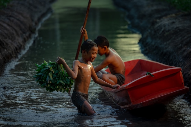 Ragazzo che gioca nella fattoria di verdure vicino al mercato galleggiante di damnoen saduak, provincia di ratchaburi