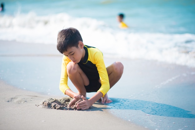 Boy playing wave and sand on the beach