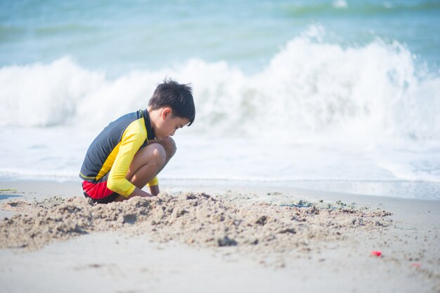 Boy playing wave and sand on the beach