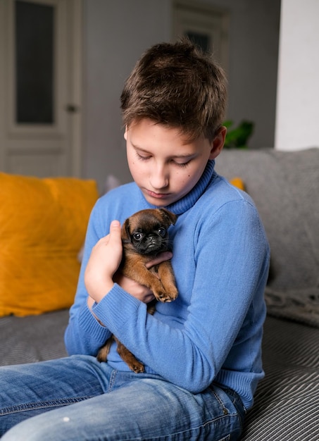 Boy playing with baby dog. Kid play with puppy at home. Little boy and griffon or brabanson dog