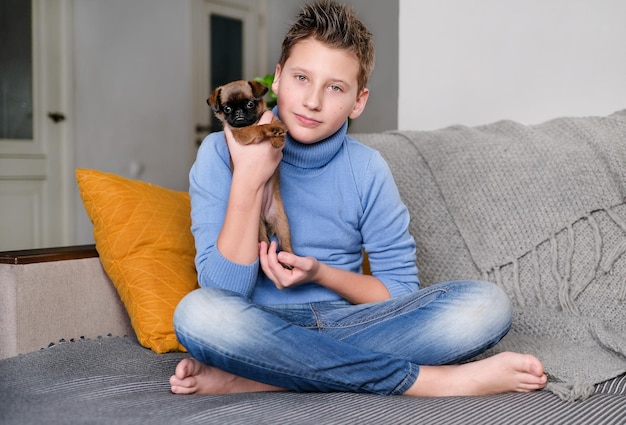 Boy playing with baby dog. Kid play with puppy at home. Little boy and griffon or brabanson dog