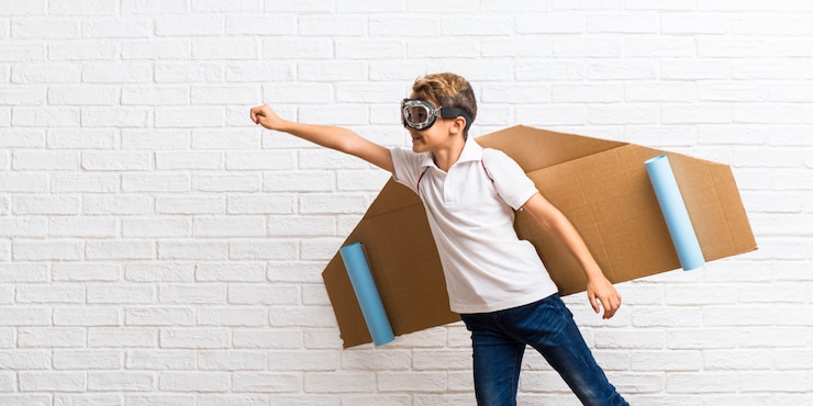 Photo boy playing with cardboard airplane wings flying