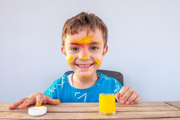 Boy playing with colors using his hands and his face