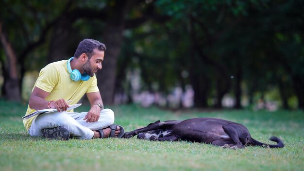 Мальчик играет с собакой, сидящей в парке