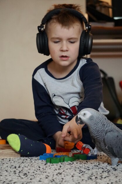 Photo boy playing with parrot at home