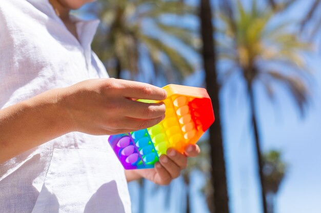 Boy playing with rainbow anti stress pop it toy outdoors