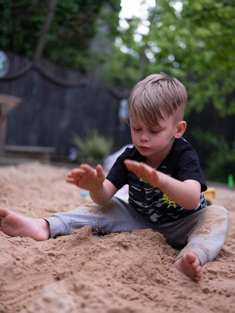 Photo boy playing with sand at park