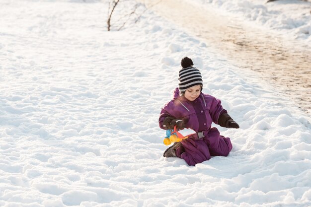 Мальчик играет с игрушкой снегоочистителя. Холодный зимний день
