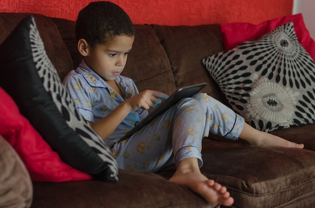 Boy playing with tablet indoor, during quarantine