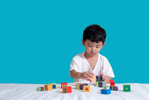 青い背景でおもちゃで遊んでいる少年