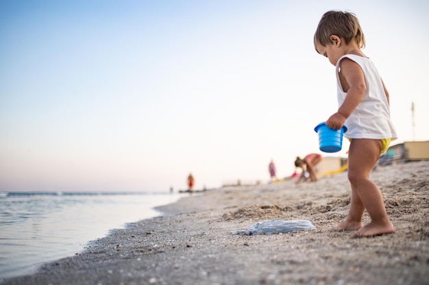 Boy playing with toys on the beach building beads and turrets smiling at someone behind the scenes on summer vacation