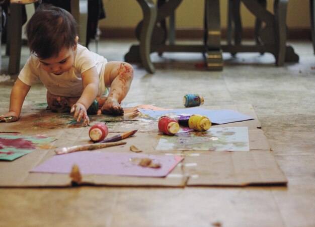 写真 床に座っている男の子が水彩画で遊んでいます