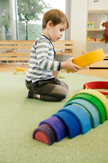 幼稚園で木の虹の形で遊ぶ男の子