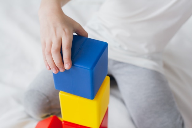 Boy plays and builds a tower of colorful plastic cubes 