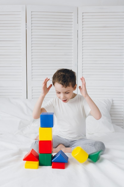 Boy plays and builds a tower of colorful plastic cubes 