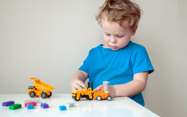 boy plays colorful multi-colored cubes and cars on the table early development and learning
