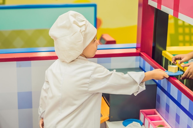 Il ragazzo gioca come se fosse un cuoco o un fornaio in una cucina per bambini