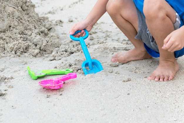 男の子はビーチで砂の中で遊ぶ