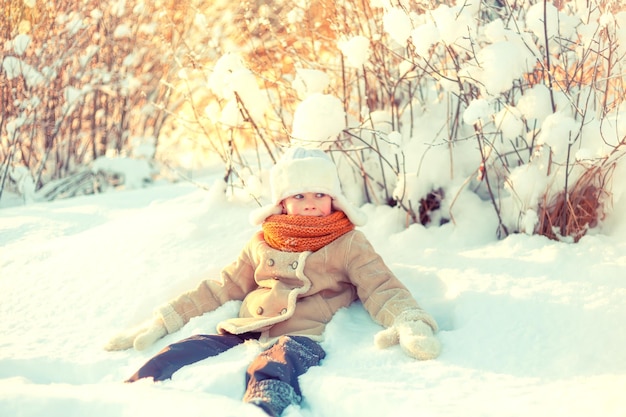 Мальчик играет в снежном зимнем лесу