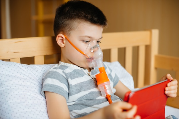 A boy plays on a tablet during a lung inhalation procedure.