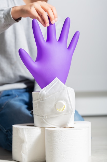 Boy plays with coronavirus symbols: toilet paper, medical gloves, protection mask