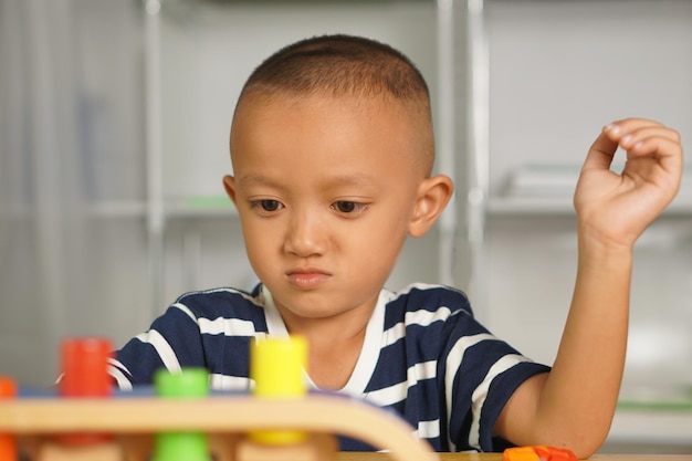 мальчик играет с развивающими игрушками на столе внутри дома. Игрушка представляет собой разноцветную кнопку, счастливые дети веселятся.