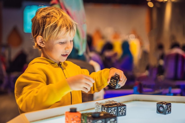 The boy plays with the electronic designer on the light table