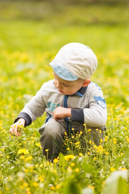 Foto il ragazzo gioca con i fiori sui prati