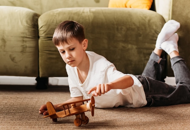 Photo a boy plays with a wooden toy plane in the living room. longing for travel