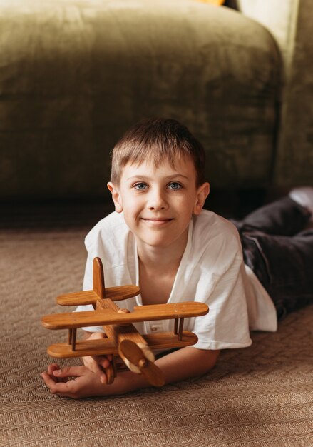 A boy plays with a wooden toy plane in the living room. Longing for travel