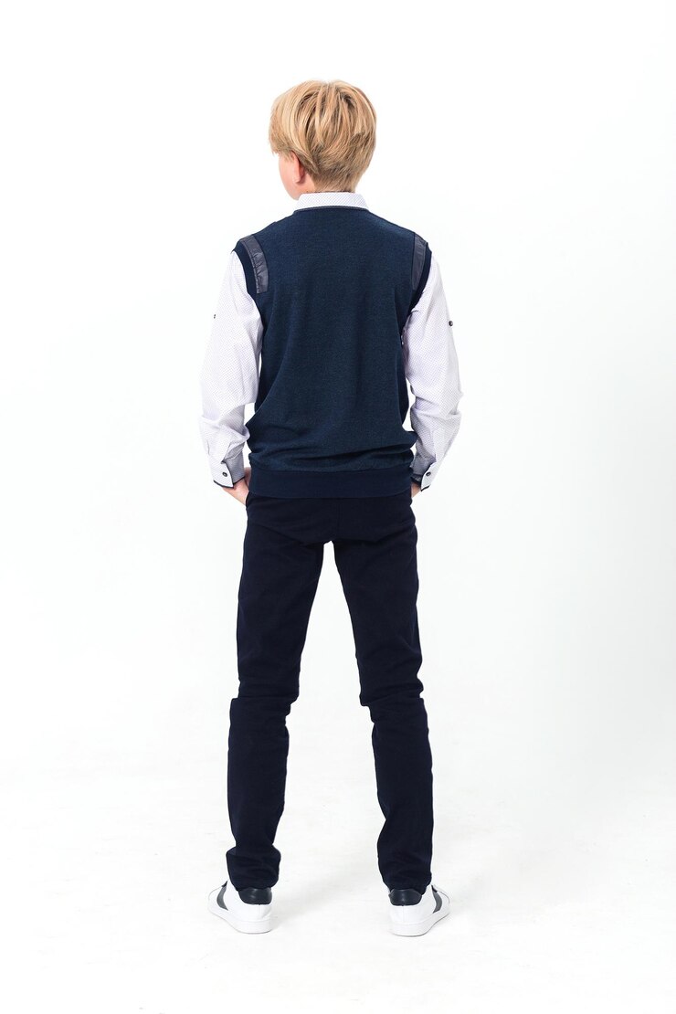 Boy posing in school uniform on white background The boy is standing with his back to the camera Vertical photo