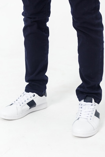 Boy posing in white sneakers and dark school pants on a white background Vertical photo