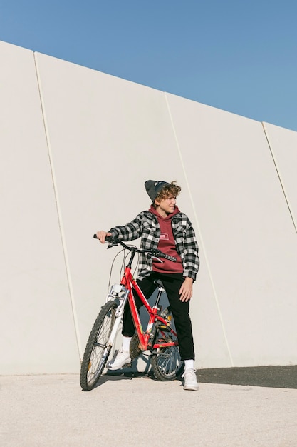 Мальчик позирует со своим велосипедом на открытом воздухе