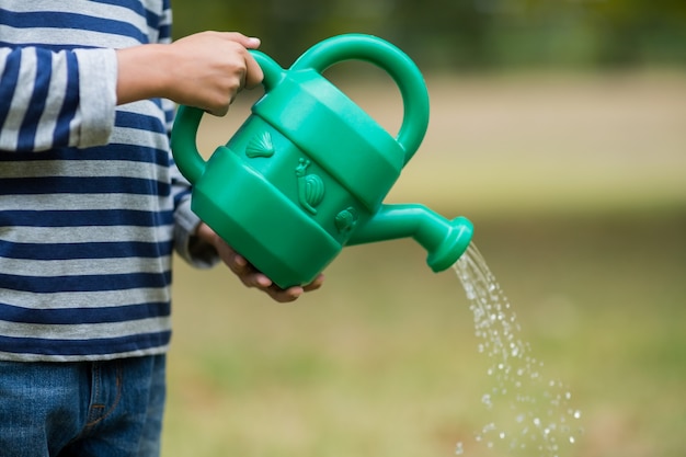 Photo boy pouring water from watering can