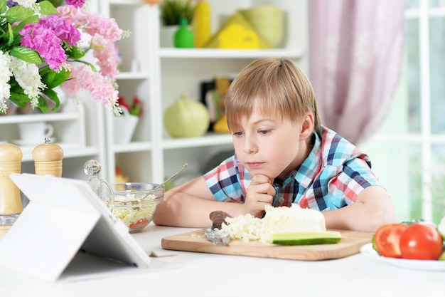 Boy preparing delicious fresh salad in kitchen