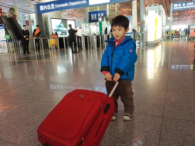 Photo boy pulling luggage at airport