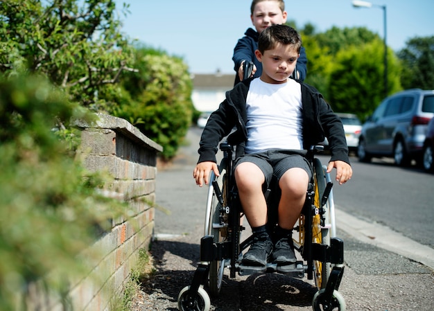 Photo boy pushing his brother in a wheelchair