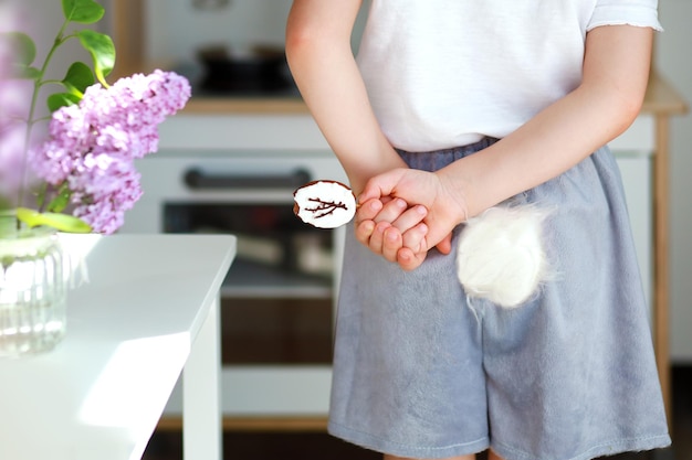 A boy in a rabbit costume hides a bitten easter cookie behind his back