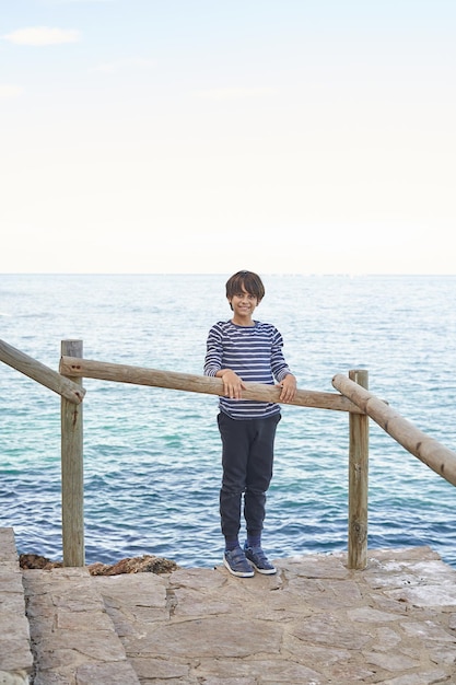 The boy on the railing playing by the sea