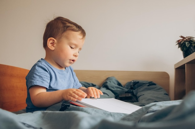 A boy reading a book in bed