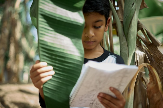 Photo boy reading book by tree