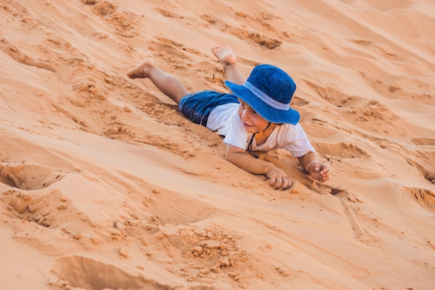 夜明けの赤い砂漠の少年。子供と一緒に旅行のコンセプト。