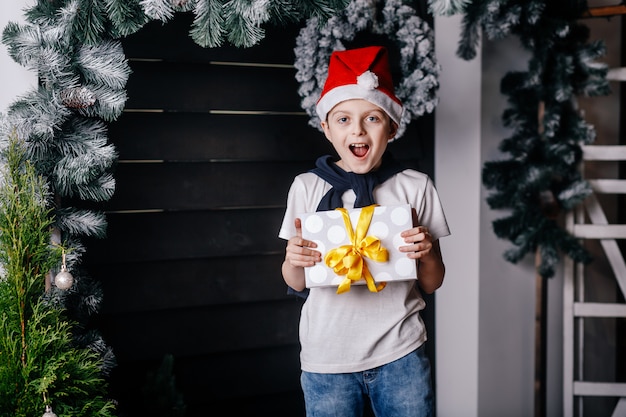 A boy in red hat is standing with a gift in his hands