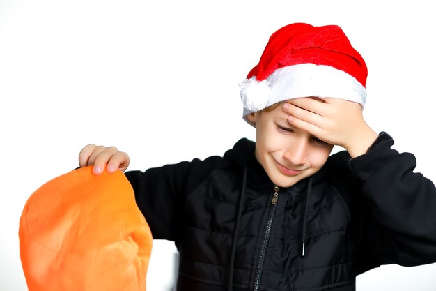 A boy in a red Santa hat holds his head