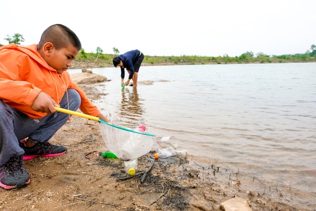 Boy removing plastic bottles from lake