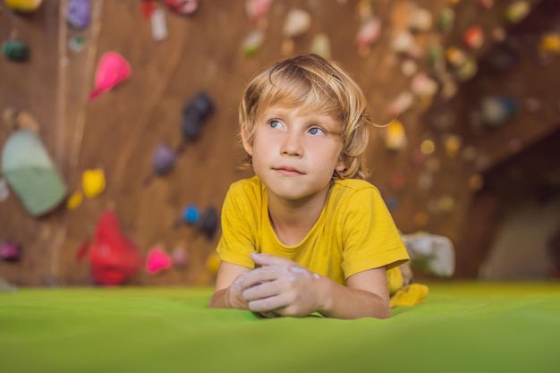 屋内の岩壁を登った後に休んでいる少年