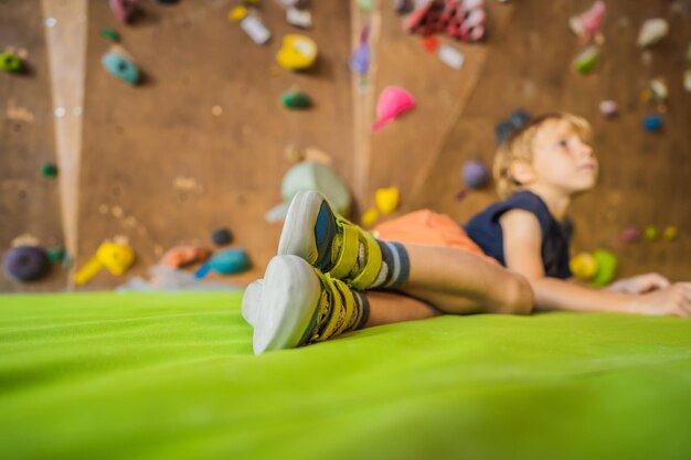 屋内の岩壁を登った後に休んでいる少年